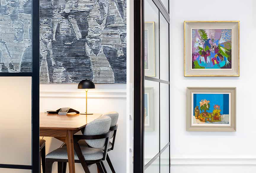 office table viewed through glass with large painting on the wall