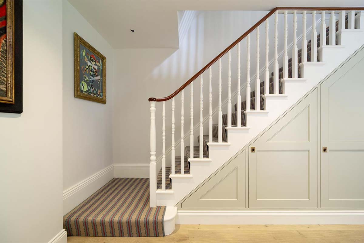 Staircase with striped carpet and wooden handrail