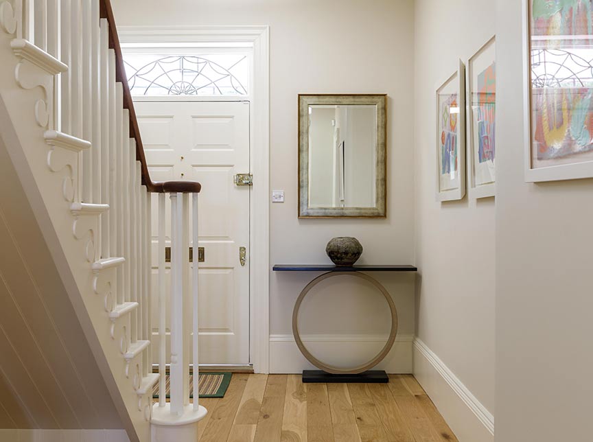 hallway with white walls, wooden floor and statement furniture